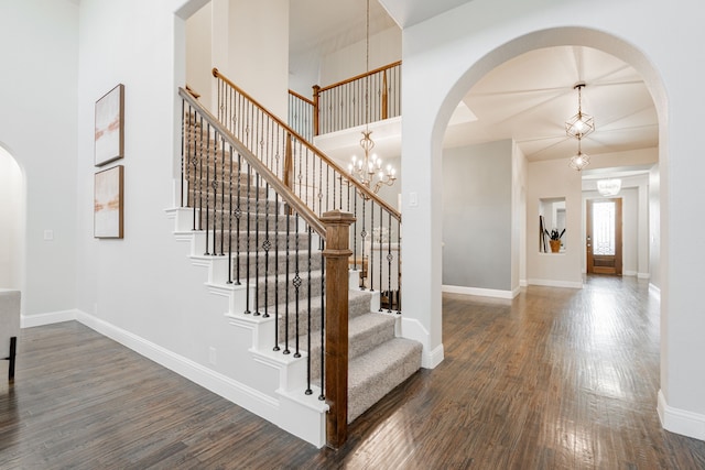 staircase with an inviting chandelier and wood-type flooring