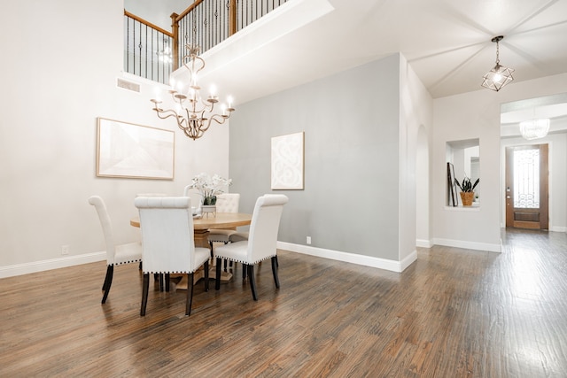 dining room featuring an inviting chandelier, a towering ceiling, and dark hardwood / wood-style floors