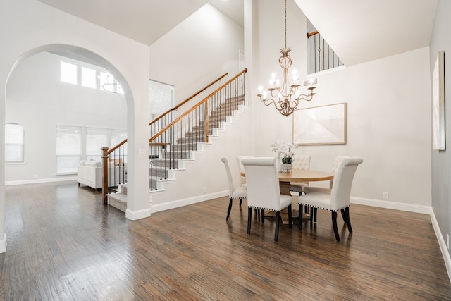 dining room featuring a towering ceiling, dark wood-type flooring, and a chandelier