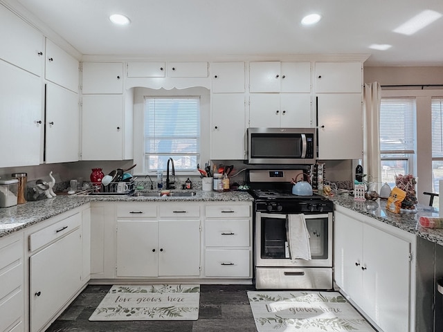 kitchen with stainless steel appliances, sink, white cabinets, and light stone counters