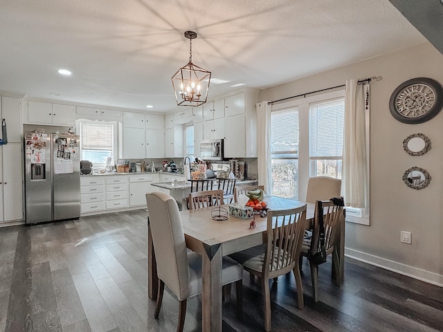 dining area with a healthy amount of sunlight, dark wood-type flooring, and an inviting chandelier