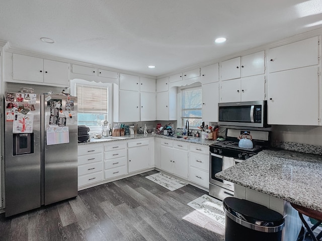 kitchen with stainless steel appliances, dark hardwood / wood-style floors, white cabinets, and light stone counters