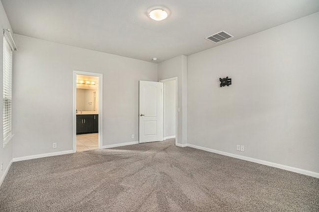 unfurnished bedroom featuring connected bathroom and light colored carpet