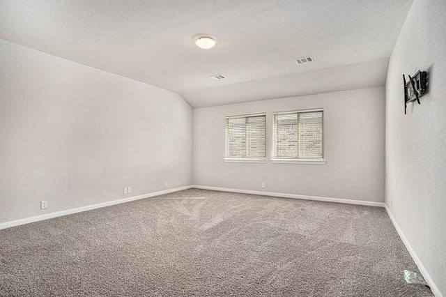 carpeted spare room featuring lofted ceiling and a textured ceiling