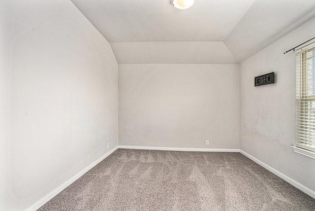 carpeted spare room featuring vaulted ceiling