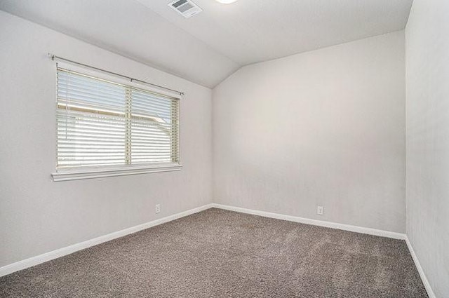 carpeted empty room with vaulted ceiling