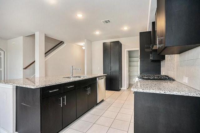 kitchen with an island with sink, appliances with stainless steel finishes, sink, and decorative backsplash