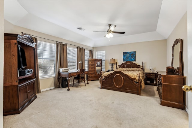 bedroom with light colored carpet, a raised ceiling, and ceiling fan