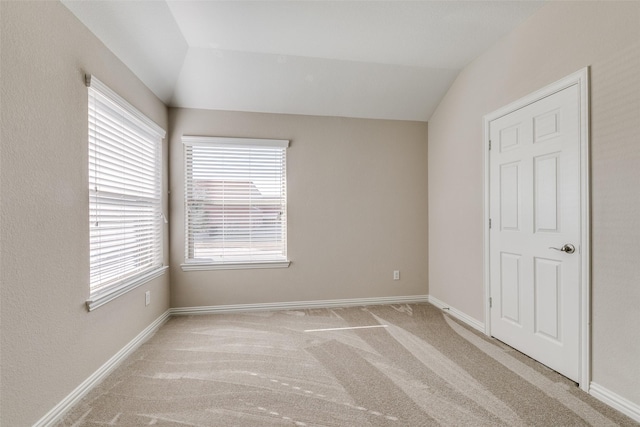 unfurnished room with vaulted ceiling and light carpet