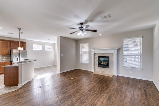 unfurnished living room with hardwood / wood-style floors, a fireplace, ceiling fan, and plenty of natural light