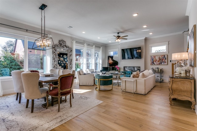 dining area featuring crown molding, ceiling fan with notable chandelier, and light hardwood / wood-style flooring