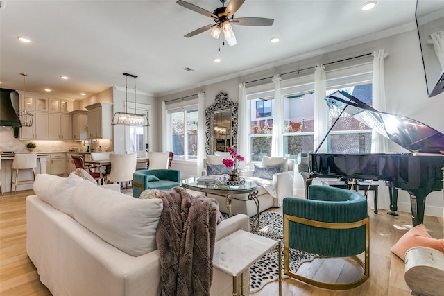 living room featuring crown molding, sink, ceiling fan, and light hardwood / wood-style flooring