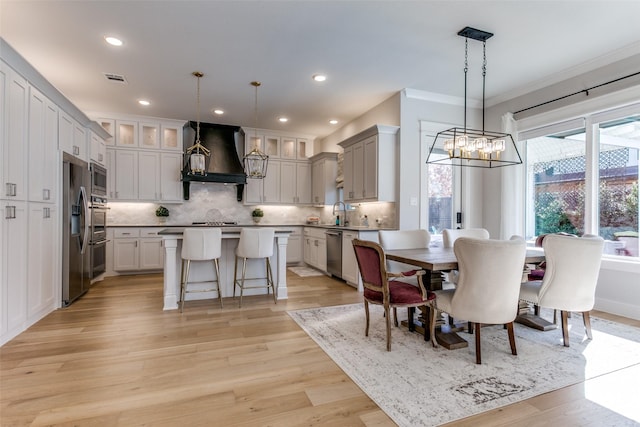 dining room with an inviting chandelier, ornamental molding, and light hardwood / wood-style floors