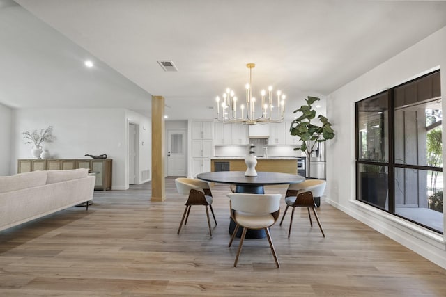 dining space with a notable chandelier and light hardwood / wood-style flooring