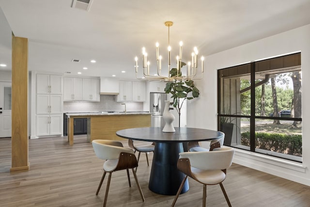 dining area featuring an inviting chandelier and light hardwood / wood-style flooring