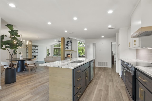 kitchen with an island with sink, sink, white cabinets, custom exhaust hood, and black range with electric cooktop