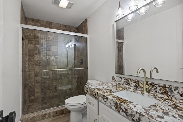 bathroom with vanity, toilet, a shower with shower door, and hardwood / wood-style floors