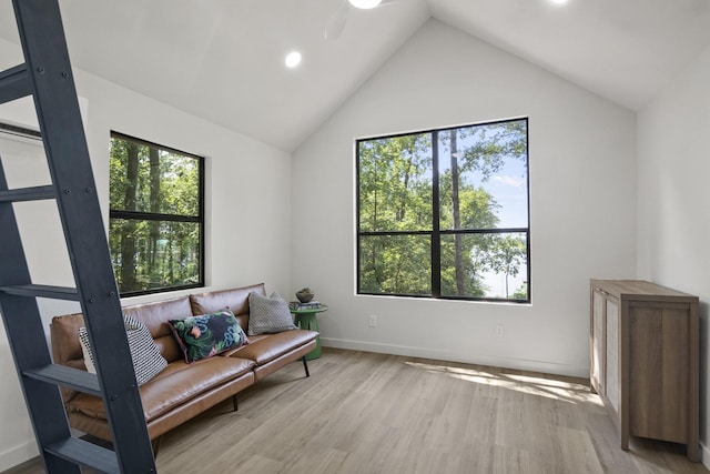 living area featuring vaulted ceiling, light hardwood / wood-style floors, and a healthy amount of sunlight