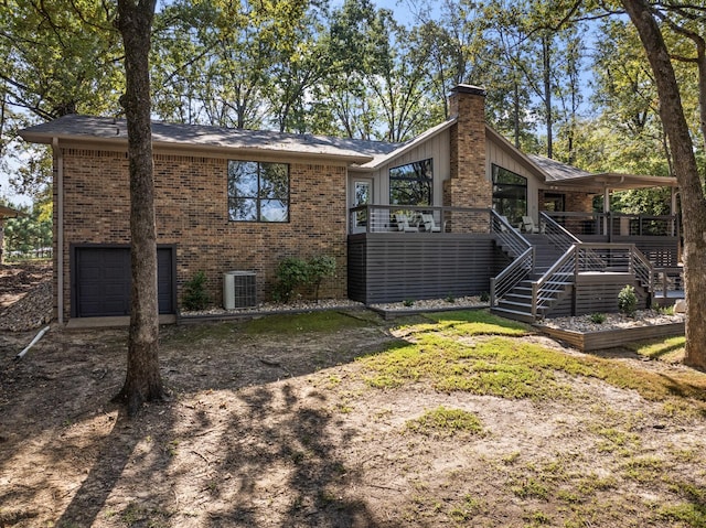 rear view of property with a garage, a wooden deck, and central air condition unit