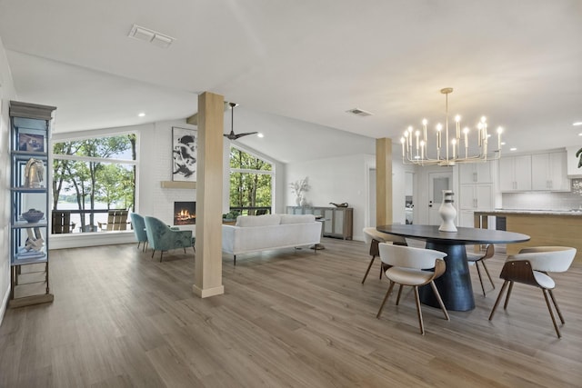 dining space with lofted ceiling, hardwood / wood-style flooring, a fireplace, and a wealth of natural light