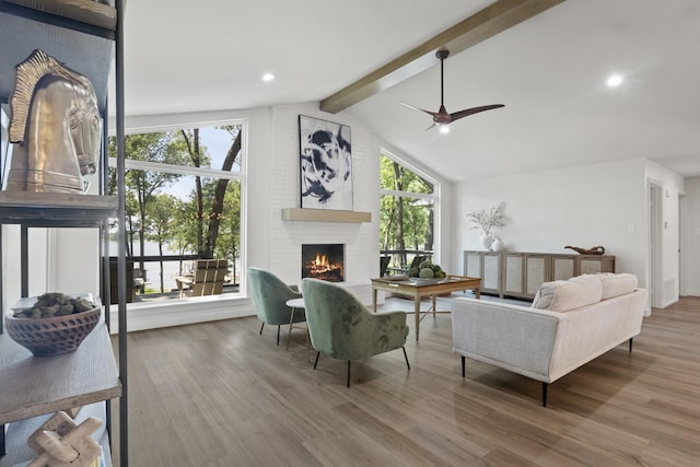 living room featuring a brick fireplace, wood-type flooring, lofted ceiling with beams, and ceiling fan