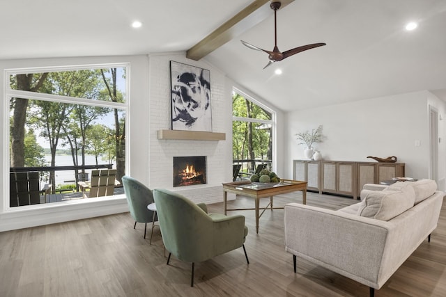 interior space with hardwood / wood-style flooring, ceiling fan, a fireplace, and vaulted ceiling with beams