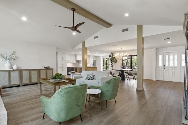 living room with ceiling fan with notable chandelier, high vaulted ceiling, beam ceiling, and light hardwood / wood-style floors