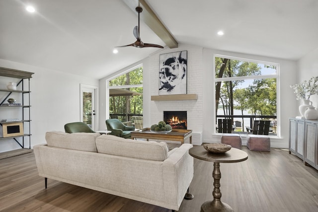 living room with hardwood / wood-style flooring, ceiling fan, a fireplace, and lofted ceiling with beams