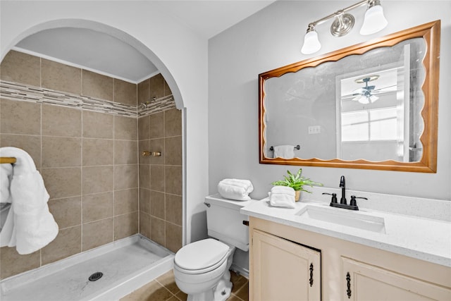 bathroom featuring tiled shower, toilet, vanity, ceiling fan, and tile patterned flooring