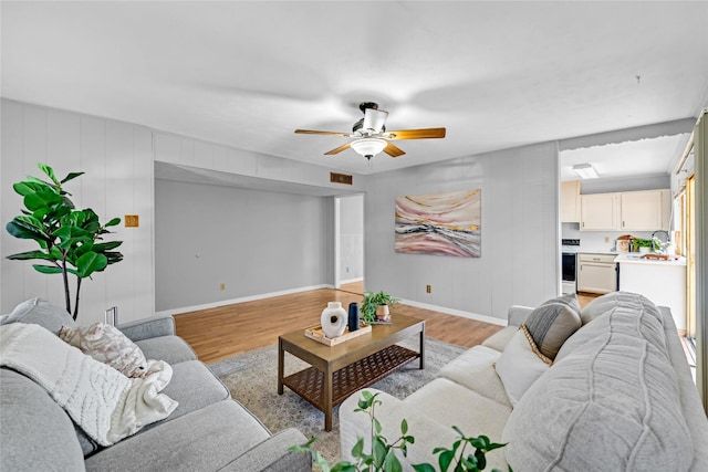 living room with ceiling fan, sink, and light hardwood / wood-style floors