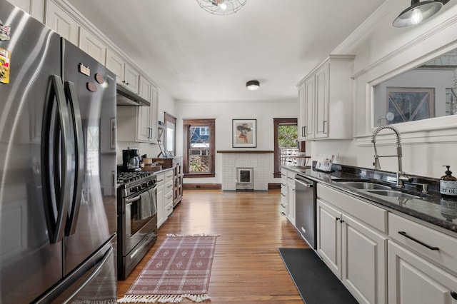 kitchen featuring stainless steel appliances, sink, white cabinets, and dark stone counters