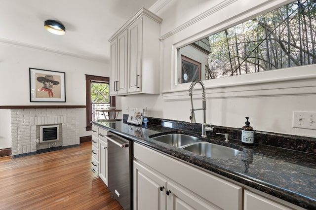 kitchen with dishwasher, sink, white cabinets, and a fireplace