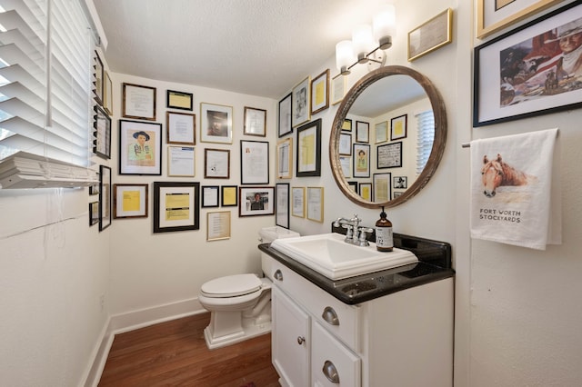 bathroom featuring vanity, hardwood / wood-style flooring, toilet, and a textured ceiling