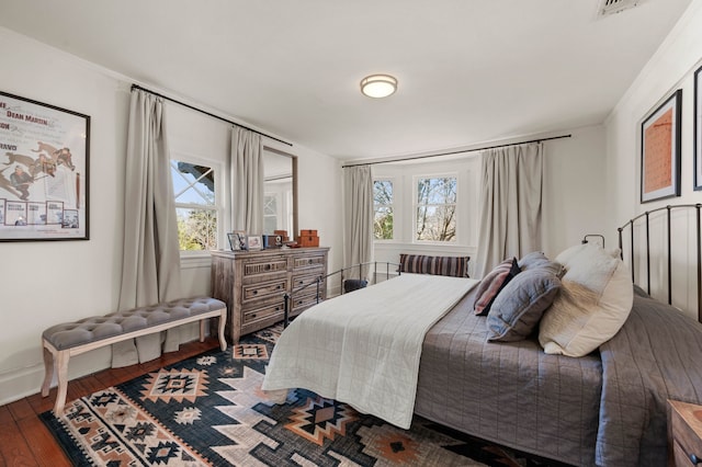 bedroom with multiple windows and dark wood-type flooring