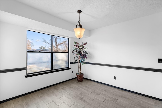 unfurnished room with a textured ceiling and light wood-type flooring