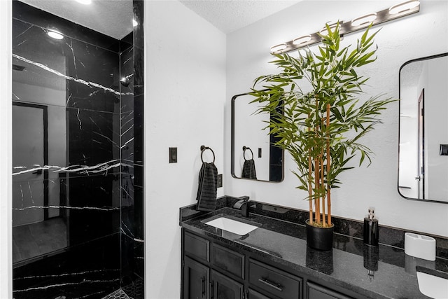 bathroom with vanity, tiled shower, and a textured ceiling