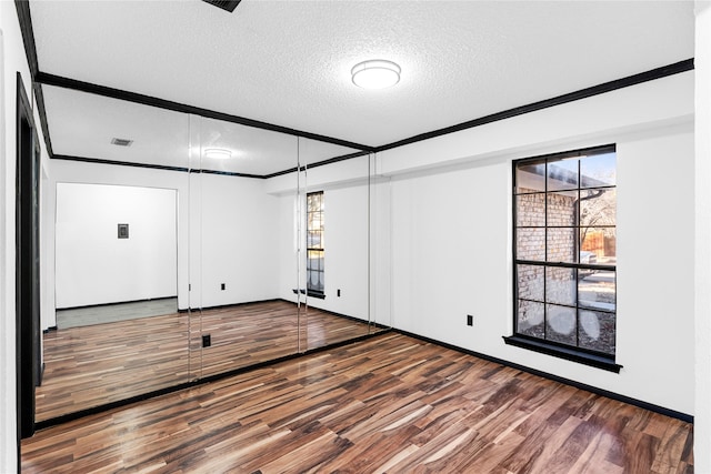 spare room featuring a healthy amount of sunlight, hardwood / wood-style flooring, ornamental molding, and a textured ceiling