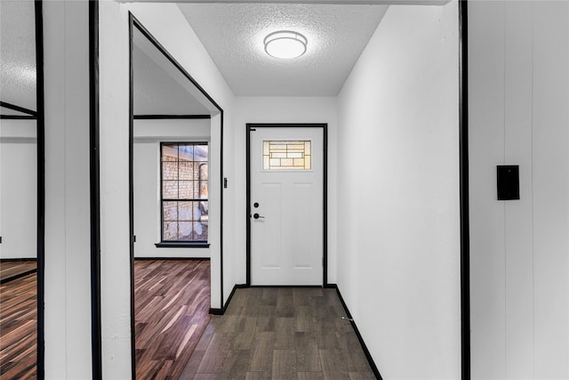 doorway with dark wood-type flooring and a textured ceiling