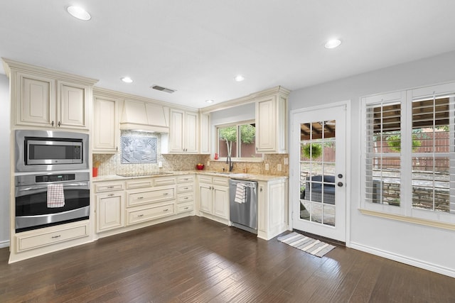 kitchen featuring custom exhaust hood, appliances with stainless steel finishes, dark hardwood / wood-style floors, and cream cabinetry