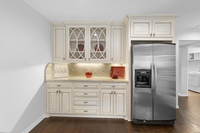 kitchen with washer / dryer, cream cabinets, backsplash, and stainless steel fridge with ice dispenser