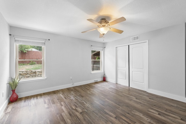 unfurnished bedroom with ceiling fan, dark hardwood / wood-style flooring, a closet, and a textured ceiling