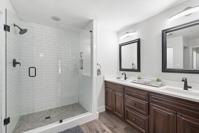 bathroom featuring hardwood / wood-style flooring, vanity, a shower with shower door, and a textured ceiling