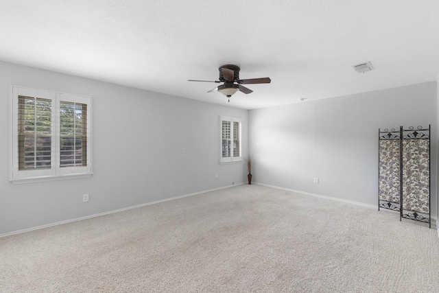 carpeted spare room featuring ceiling fan and a healthy amount of sunlight