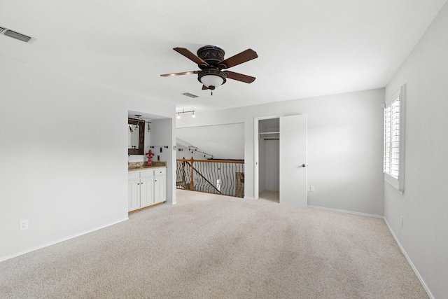 unfurnished living room featuring light carpet and ceiling fan