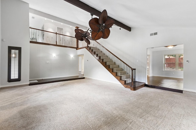 unfurnished living room with beam ceiling, ceiling fan, carpet, and high vaulted ceiling