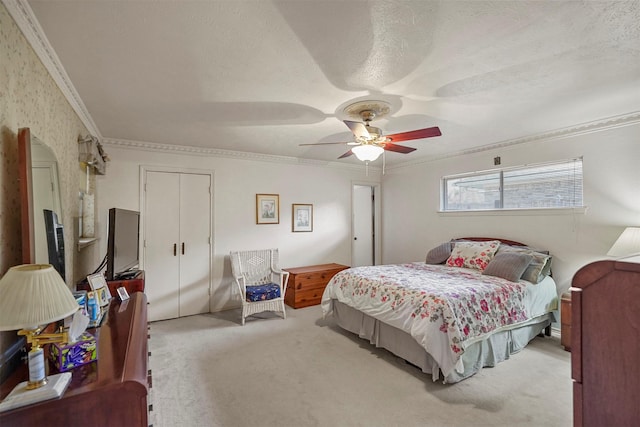 carpeted bedroom featuring ceiling fan, ornamental molding, a closet, and a textured ceiling