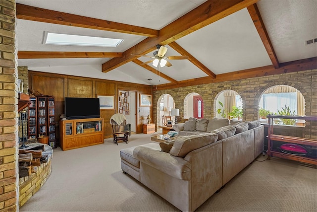 carpeted living room featuring lofted ceiling with skylight, brick wall, wood walls, ceiling fan, and a textured ceiling