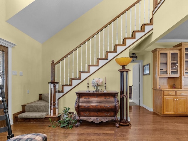 foyer with hardwood / wood-style floors, a towering ceiling, and ornamental molding