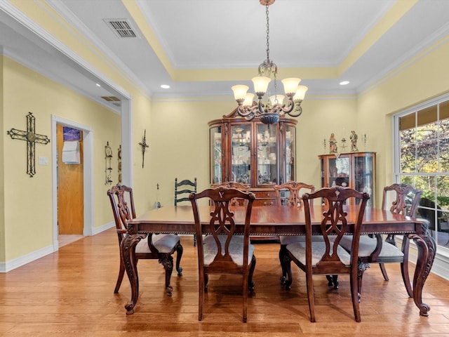 dining space featuring a raised ceiling, crown molding, and a notable chandelier