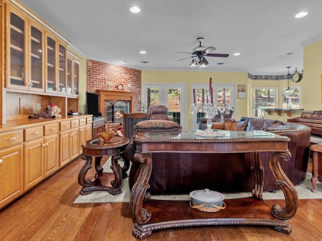 living room with crown molding, a fireplace, a healthy amount of sunlight, and light wood-type flooring